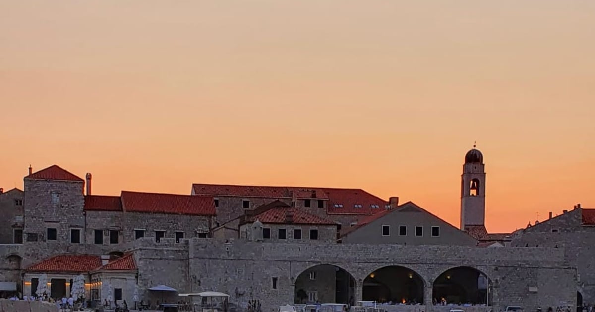 Dubrovnik’s old harbour and bell tower in golden light, seen from the back of a sunset boat