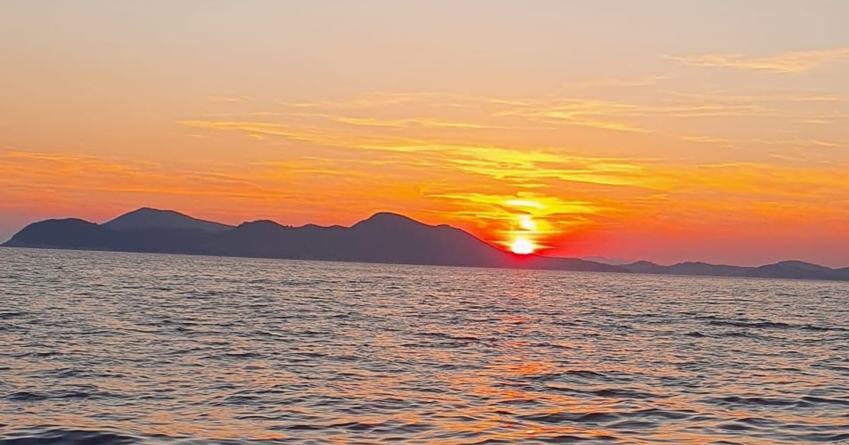 The sun setting behind a line of islands, seen from a moving boat off Dubrovnik
