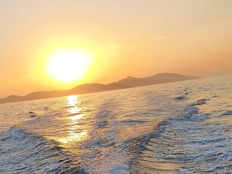 Low sun over the islands and the white wake behind the boat
